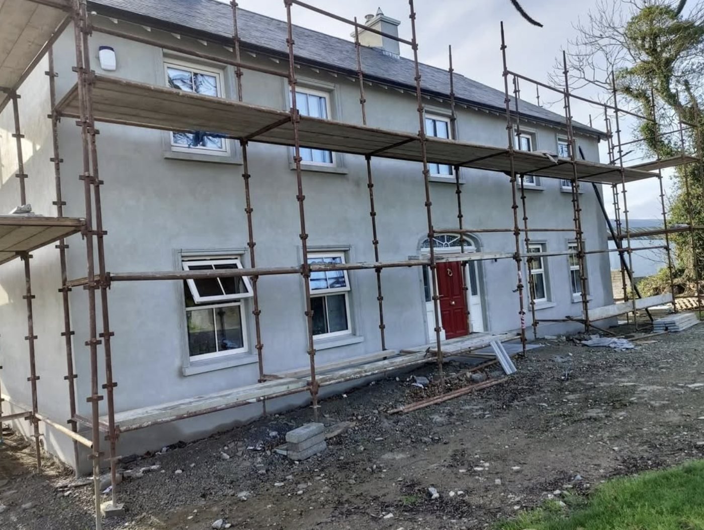 Long two-storey house in a grey basecoat with scaffolding still up