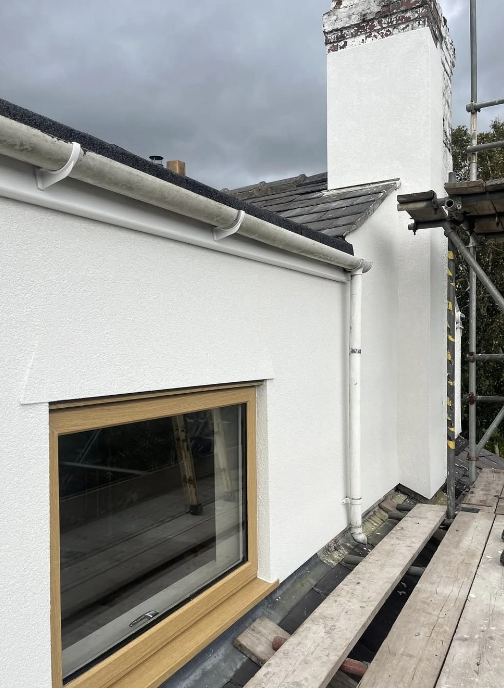 Chimney stack and dormer side in a new white finish, seen from the scaffold