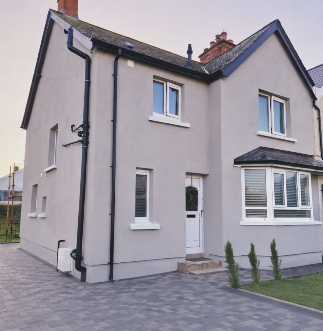 Semi-detached house in a warm grey finish with a slightly darker plinth band
